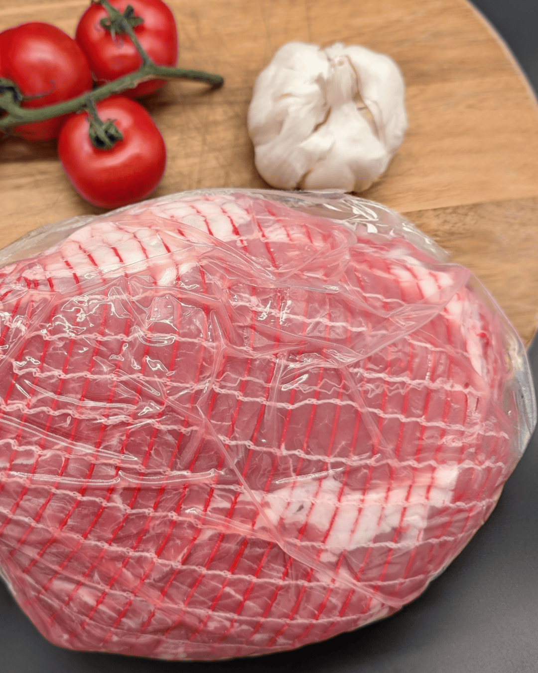 Gammon Slipper Joint on a chopping board with tomato and garlic