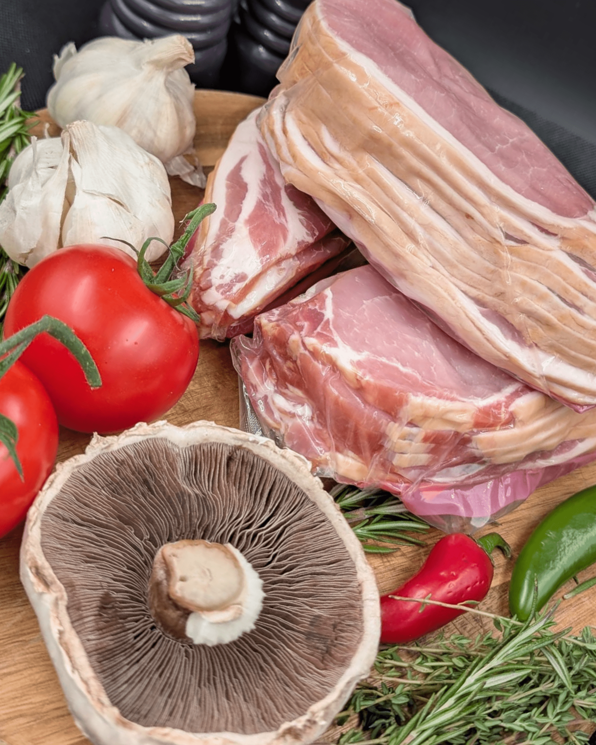 Selection of smoked back bacon with various vegetables and herbs